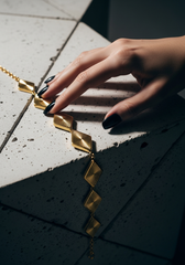 Editorial joyería pulsera dijes rombo sobre superficie geométrica | Gheller