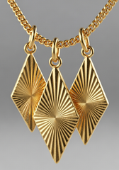 Detalle macro dijes rombo dorados con textura sunburst rayada | Gheller Joyería