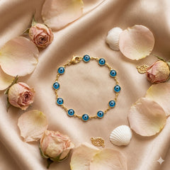Pulsera ojo turco dorada con cuentas azules sobre seda con pétalos de rosa | Gheller Joyería