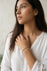 Mujer con pulsera ojo turco dorada, blusa blanca off-shoulder | Gheller Joyería