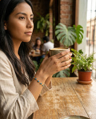 Detalle pulsera ojo turco en café con plantas, estilo lifestyle | Gheller