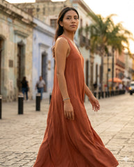 Modelo con pulsera ojo turco caminando en calle colonial, vestido terracota | Gheller