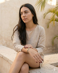 Modelo con pulsera ojo turco sentada en patio, top lino beige | Gheller Joyería