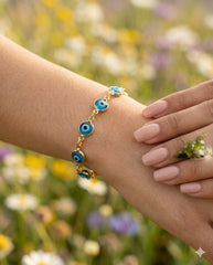 Pulsera ojo turco azul en muñeca entre flores silvestres del campo | Gheller