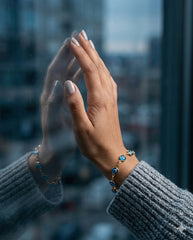 Pulsera ojo turco dorada con reflejo en ventana, estilo editorial moody | Gheller