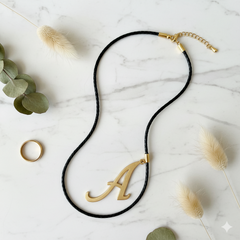 Dije inicial A en oro laminado 18k — composición flatlay con accesorios