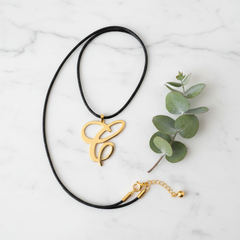 Dije inicial C en oro laminado 18k — composición flatlay con accesorios