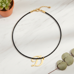 Dije inicial D en oro laminado 18k — composición flatlay con accesorios