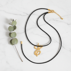 Dije inicial E en oro laminado 18k — composición flatlay con accesorios