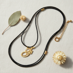 Dije inicial F en oro laminado 18k — composición flatlay con accesorios