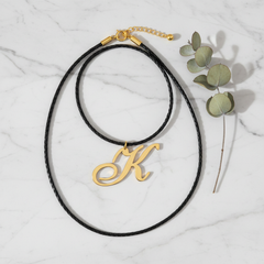 Dije inicial K en oro laminado 18k — composición flatlay con accesorios