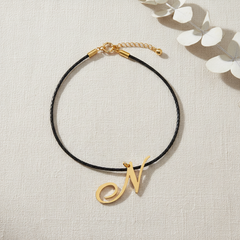 Dije inicial N en oro laminado 18k — composición flatlay con accesorios