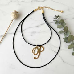Dije inicial P en oro laminado 18k — composición flatlay con accesorios