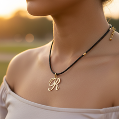 Modelo usando collar de inicial R en oro laminado con cordón de cuero negro