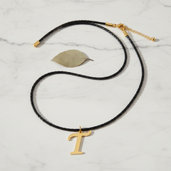 Dije inicial T en oro laminado 18k — composición flatlay con accesorios