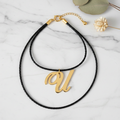 Dije inicial U en oro laminado 18k — composición flatlay con accesorios