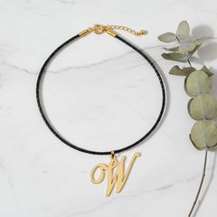 Dije inicial W en oro laminado 18k — composición flatlay con accesorios