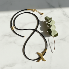 Dije inicial X en oro laminado 18k — composición flatlay con accesorios