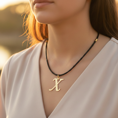 Modelo usando collar de inicial X en oro laminado con cordón de cuero negro